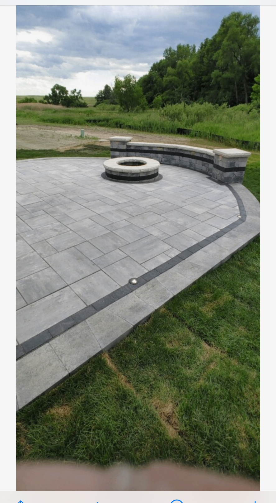 Curved paver patio with built-in fire feature and seat wall