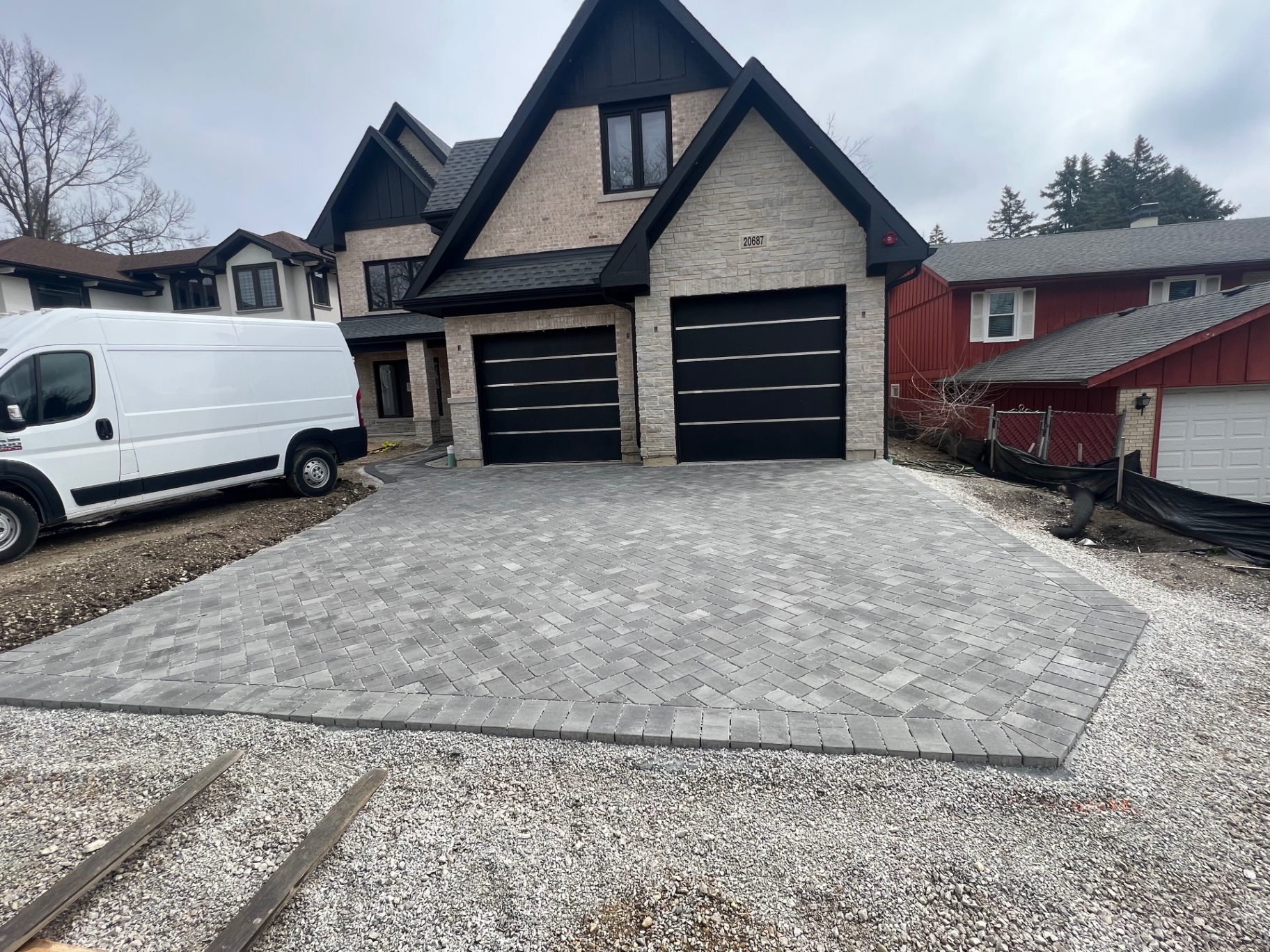 Herringbone-pattern paver driveway with contrasting border at a new luxury home